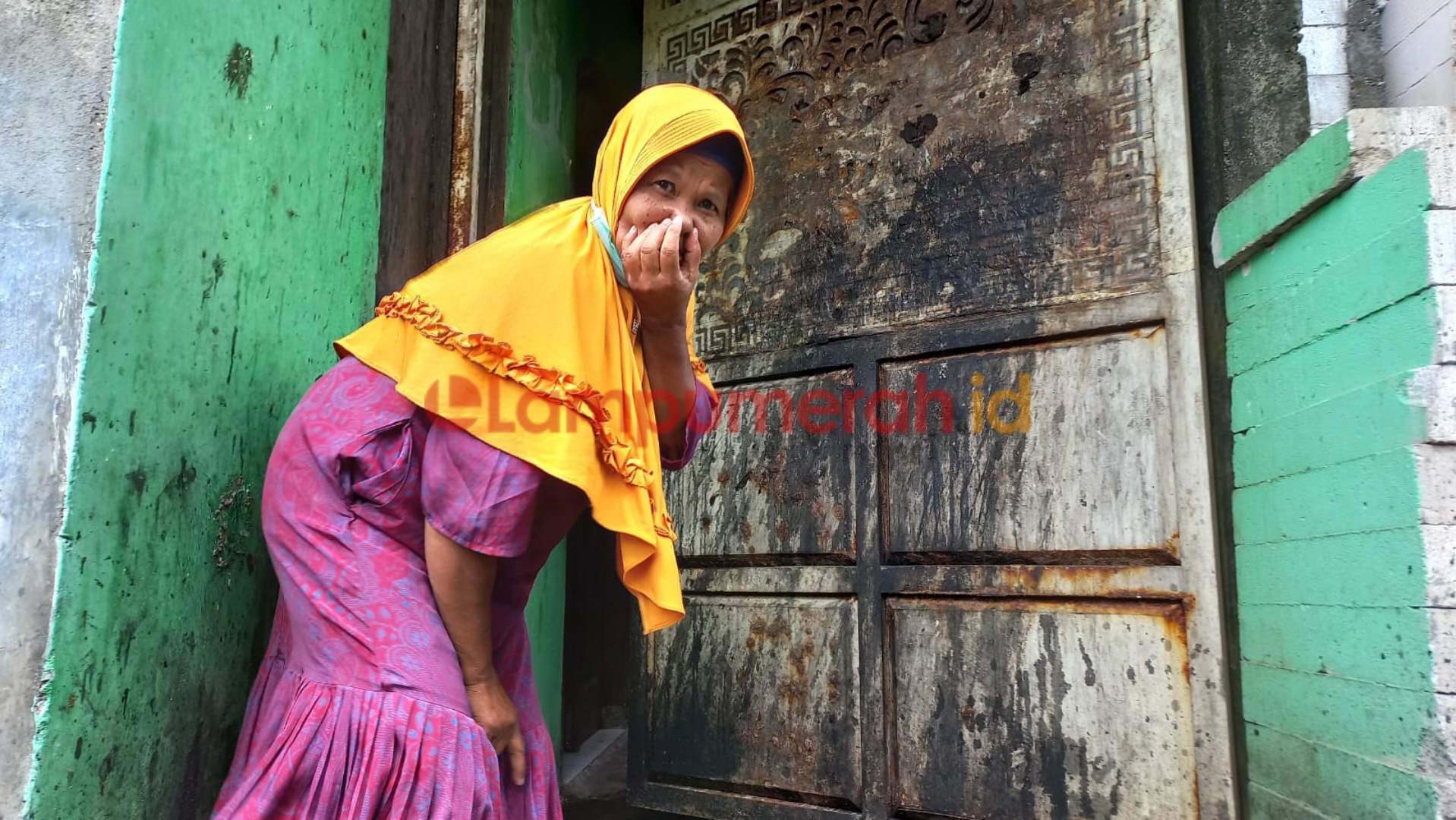 Teks foto : Korban saat menunjukkan pintu gerbang yang rusak berkarat dan berbau kotoran manusia