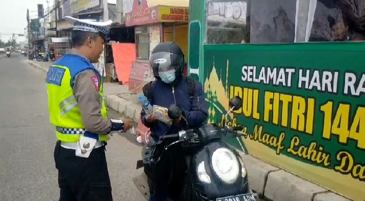 Tertangkap kamera wartawan. Sebagai bentuk apresiasi, seorang pemudik pengendara sepeda motor memberikan minuman mineral dan roti kepada petugas lalu lintas Polres Serang yang sedang mengatur arus lalu lintas dibawah terik matahari. (Foto : Daeng Yus)